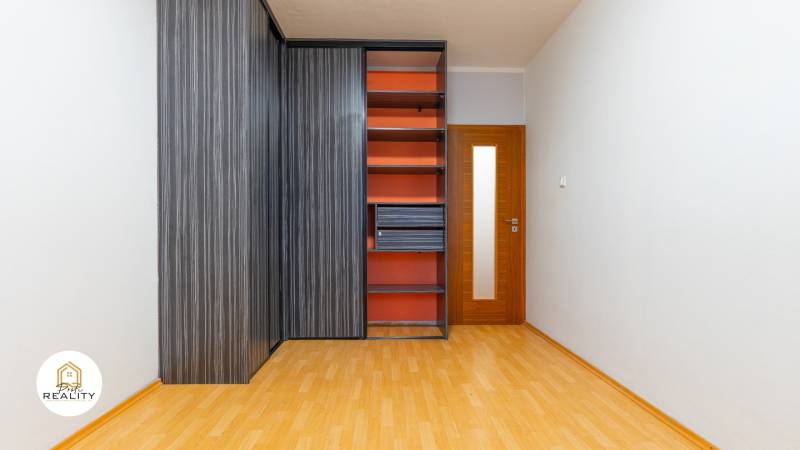 A wardrobe with integrated shelves and a floor with a wood decor in a 4-room apartment.