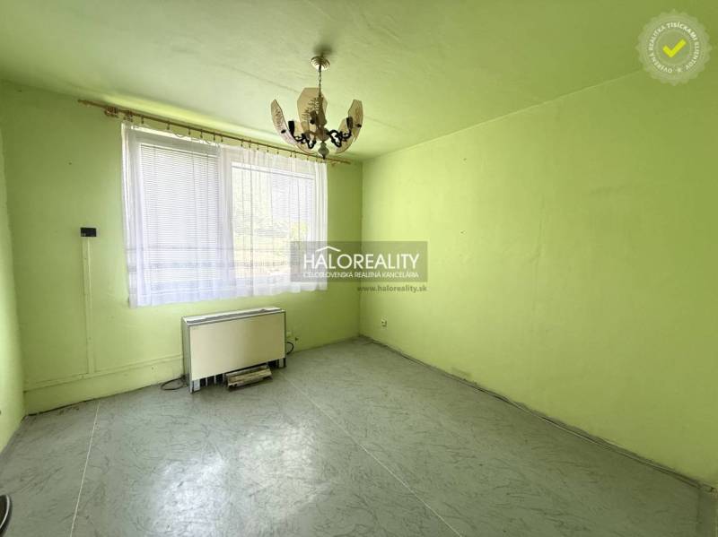 A room with a chandelier, a window, and a heating unit in a three-room apartment.