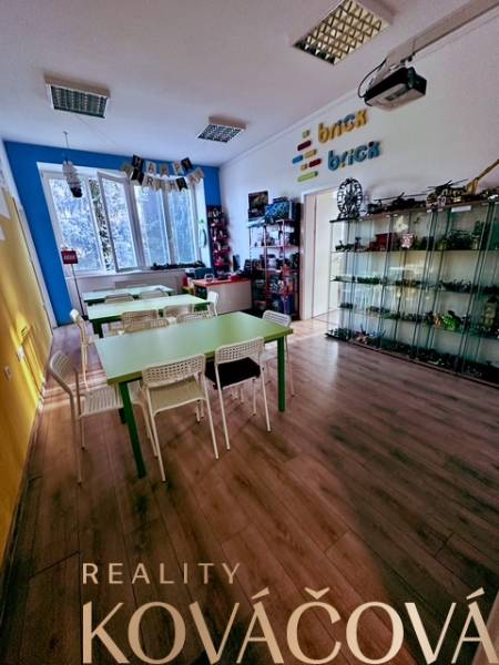 Interior of an office with wood-patterned flooring and tables, shelves with Brick toys.