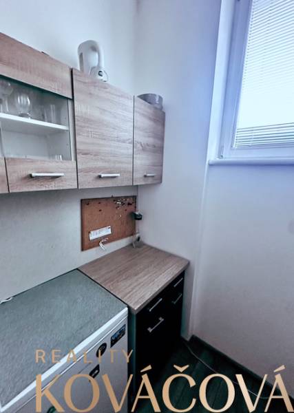 Offices with a kitchenette, cabinets with a wood finish, and a small window for lighting.