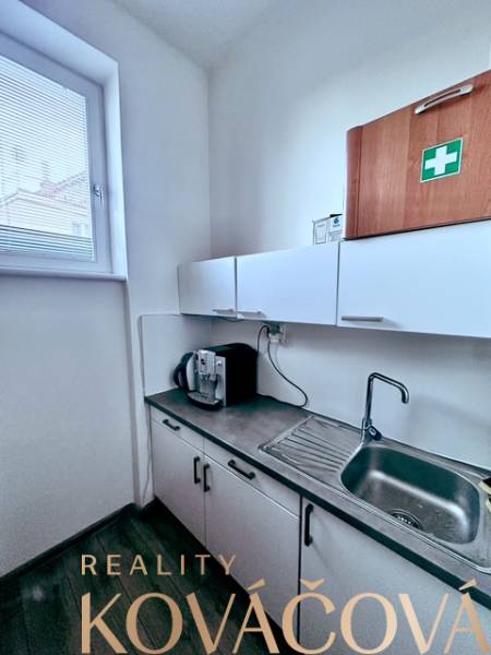 A kitchenette in the office with cabinets, a sink, and a coffee maker.