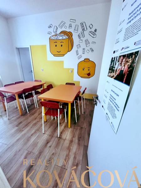 Children's corner with colorful tables, chairs, and a wooden-patterned floor in the office.