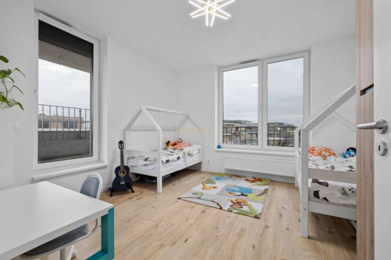 Children's room with two beds, a desk, a carpet, and a floor with a wooden decor.