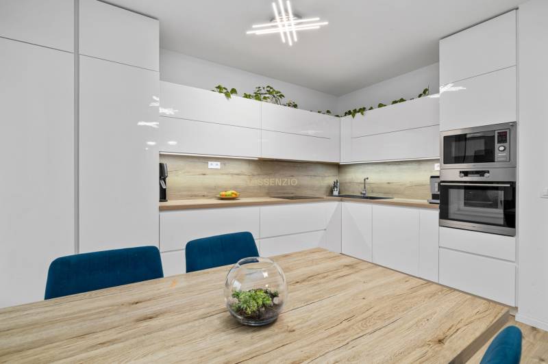 A kitchen in a 3-room apartment with white cabinets and a wood-patterned floor.