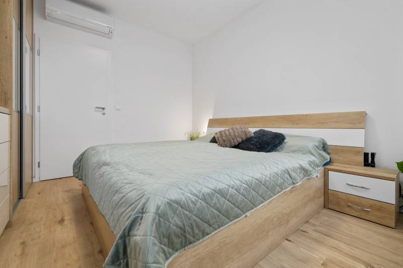 A bedroom in a 3-room apartment with light furniture and a wooden decor floor.
