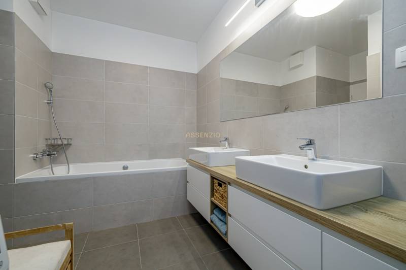 Bathroom with a bathtub, two sinks, and a mirror in a 3-room apartment.