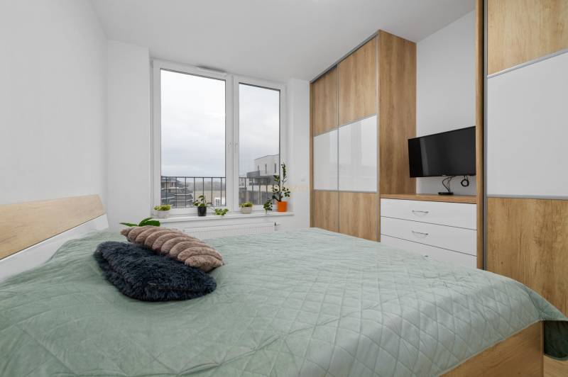 A bedroom with a large window, a bed, and a wardrobe in a 3-room apartment.