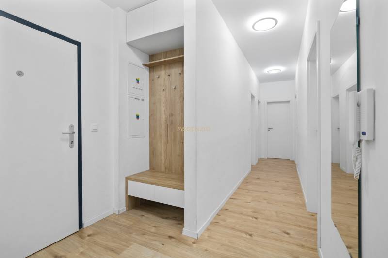 A hallway in a 3-room apartment with a wood-patterned floor and white walls.