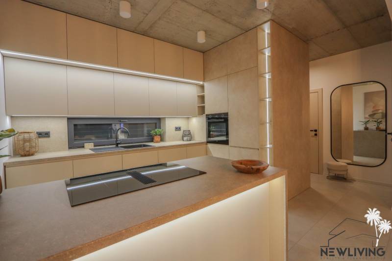 A kitchen in a family house with built-in appliances, countertops, and flooring with a wood design.