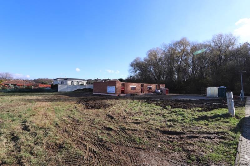 The construction site of a family house in Nitra on Drieňová Street, surrounded by nature and neighboring buildings.