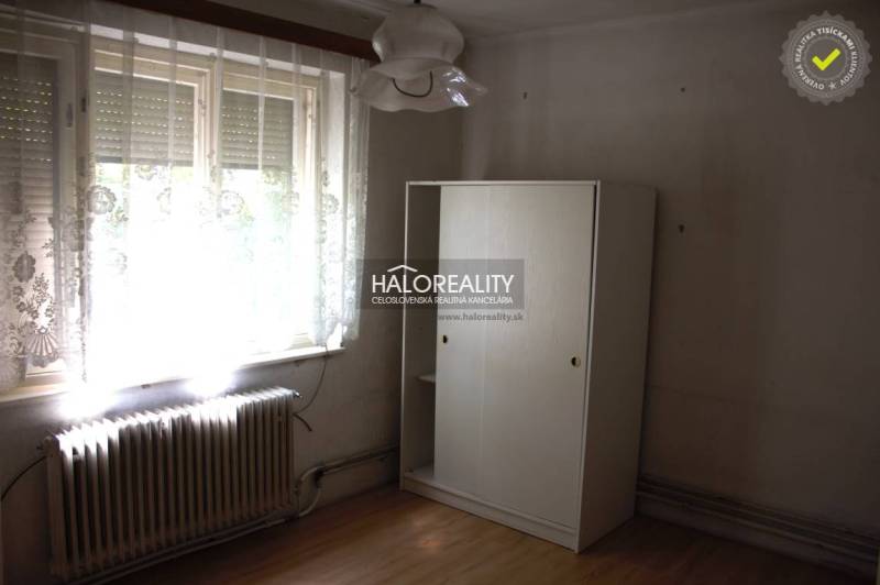 A room in a family house with a large window, a radiator, and a white wardrobe.