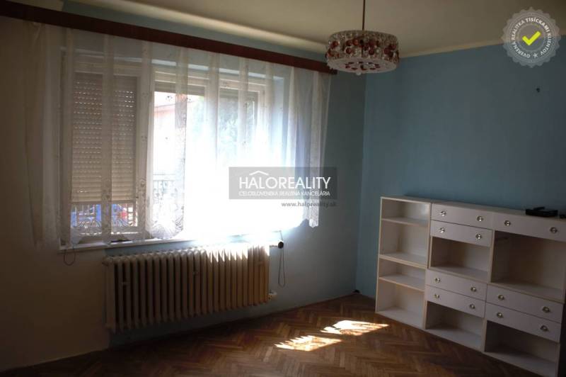 A room in a family house with a wooden decor floor, a blue wall, and a white wardrobe.