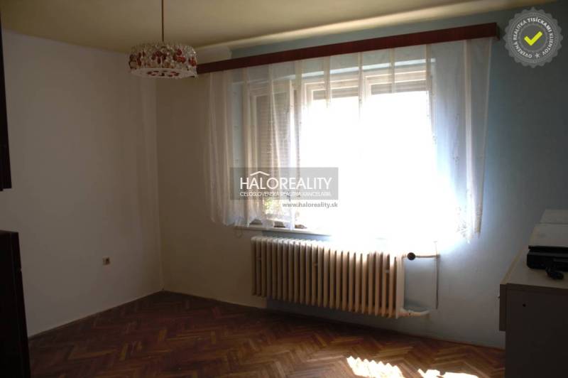 A room with curtains and a radiator, a floor with a wooden decor in a family house.