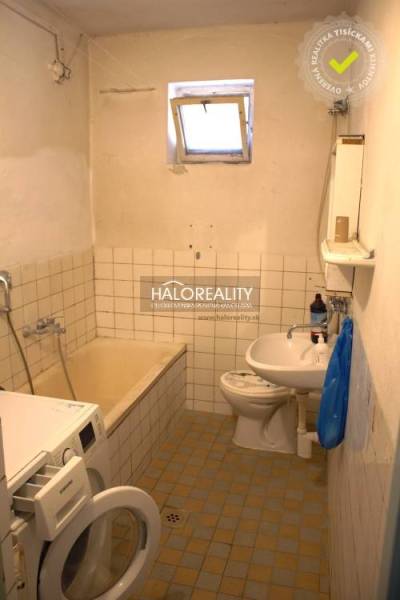 Bathroom with an older bathtub, sink, and washing machine in a family house.