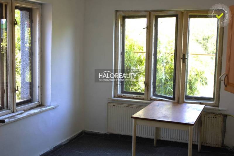 Bright room in a family house with windows, an older table, and a dark floor.