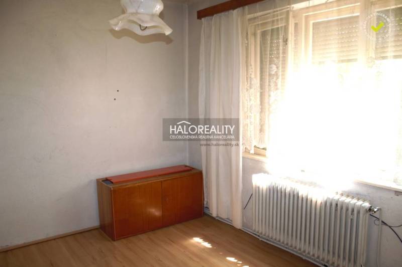 A room in a family house with a floor with a wooden decor, furniture, and a radiator.