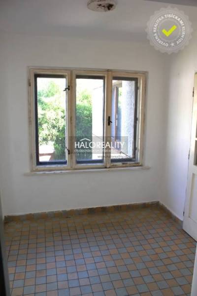 A room in a family house with a tiled floor and windows facing greenery.