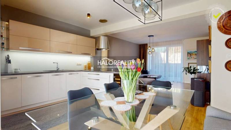 A kitchen connected to the living room, a glass table with flowers, a family house, modern lighting.