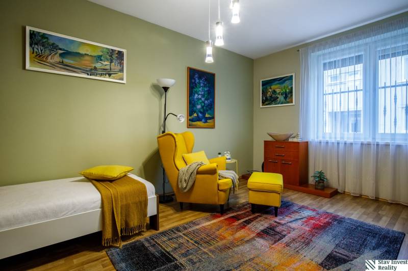 A room in a family house with a colorful carpet and a yellow armchair, wooden decor flooring.