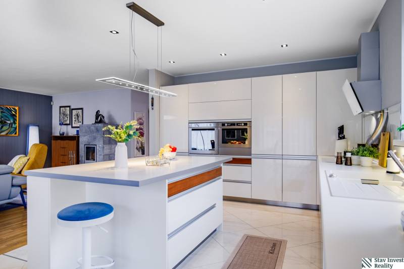 A kitchen in a family house with an island, a light fixture, a built-in oven, and accessories.