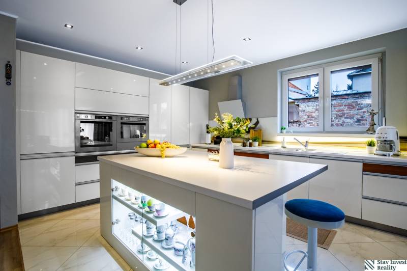 A kitchen in a family house with a central island, white cabinets, and appliances.