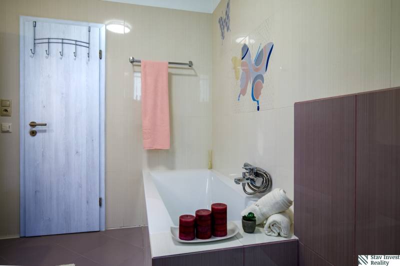 A bathroom in a family house with a bathtub, a pink towel, and decorative candles.