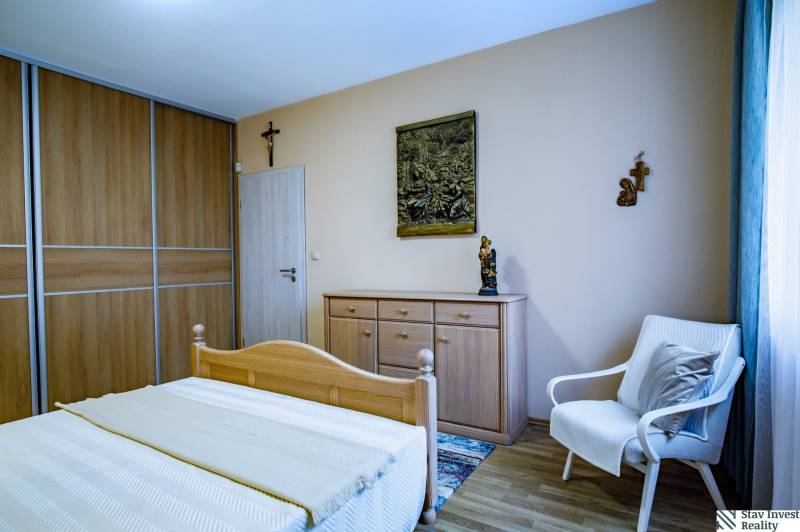 Bedroom in a family house with wooden furniture, bed, wardrobe, armchair, floor with wooden decor.