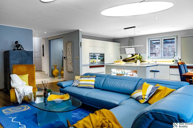 Living room in a family house with a blue sofa and a kitchen, floor with wood decor.