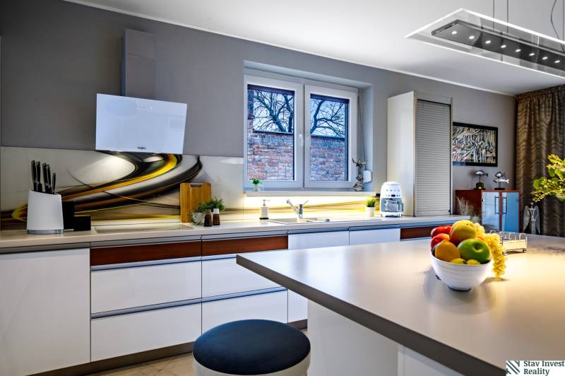 A kitchen in a family house with a stylish countertop, white cabinets, and window decorations.