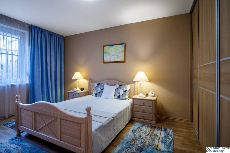 Bedroom in a family house with a bed, nightstands, and a floor with a wooden decor.