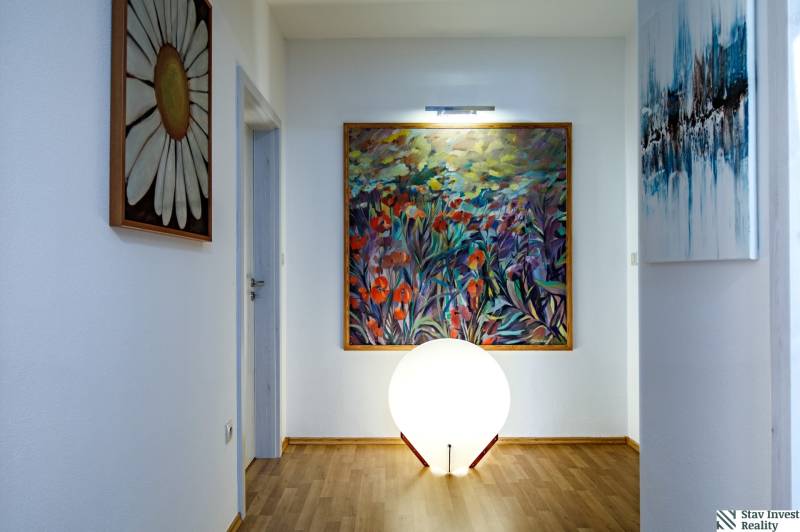 Interior of a family house with artworks on the walls, floor lighting with wooden decor.