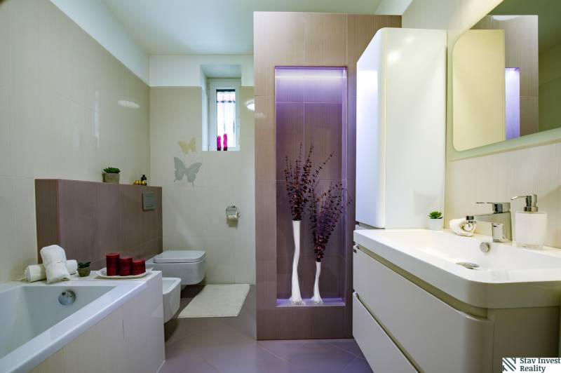 A bathroom in a family house with a bathtub, storage spaces, and decorative lighting.