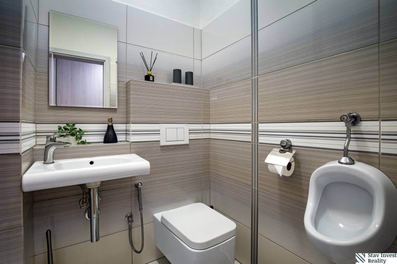 A bathroom in a family house with a sink, toilet, and tiles in neutral tones.