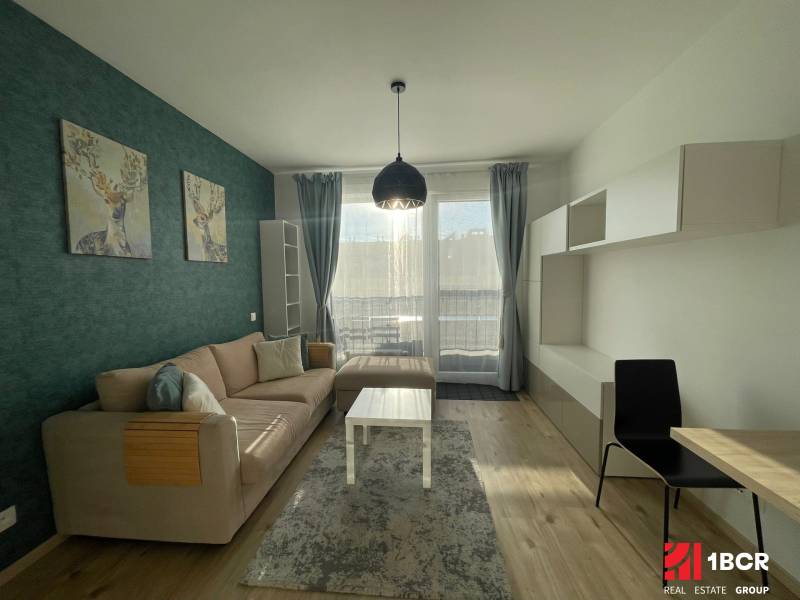 Living room of a one-room apartment with a sofa, deer decoration, and wooden decor flooring.