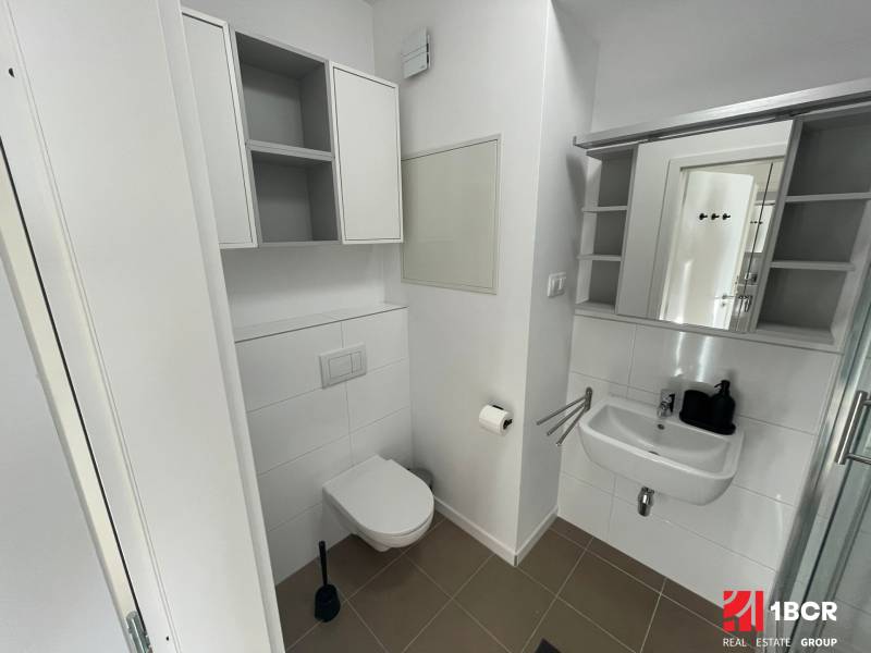 Bathroom with a sink and toilet, equipped with storage cabinets and a mirror.