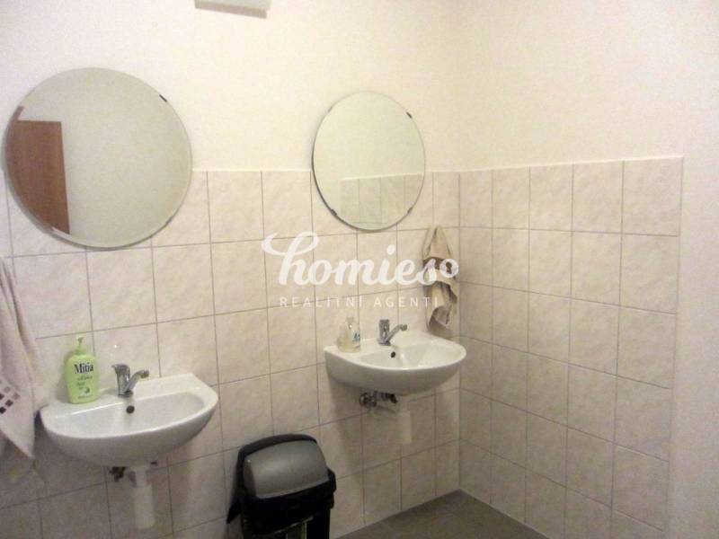 A bathroom with two sinks and round mirrors in an office.