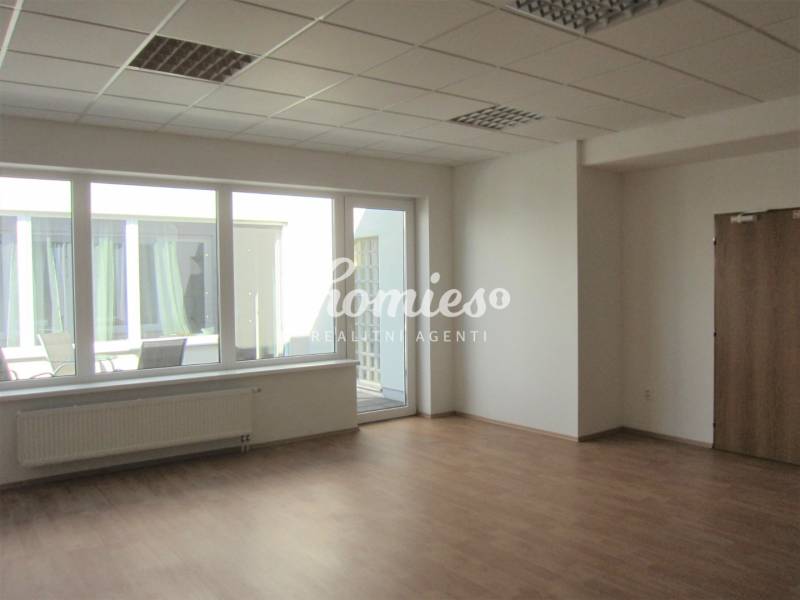 A spacious office with large windows and a wooden decor floor.