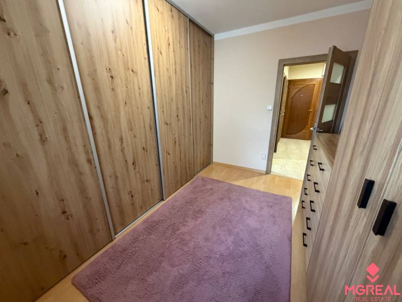 A hallway in a 4-room apartment with carpet and flooring with a wood design.