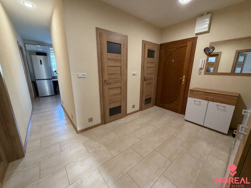 Hallway interior with entrance doors and wood-decor flooring in a 4-room apartment.