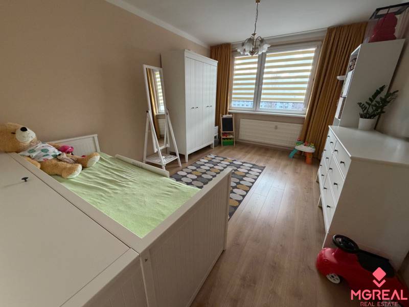 Children's room with wood decor flooring in a 4-room apartment, with white furniture.