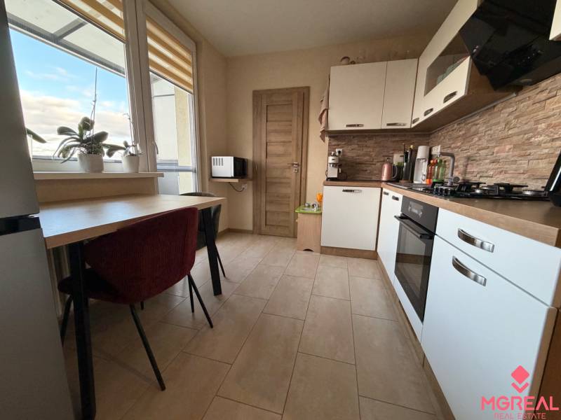 A kitchen in a 4-room apartment with a window, plants, kitchen unit, and built-in appliances.