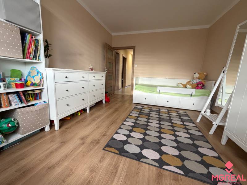 Children's room with a bed, carpet, and wooden decor flooring in a 4-room apartment.