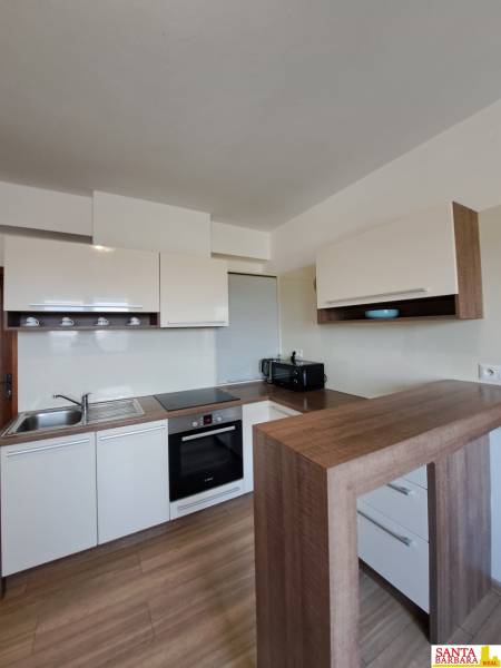 A kitchen in a 4-room apartment with white cabinets and a wooden decor floor.