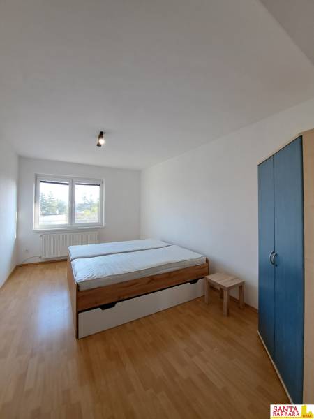 A bedroom in a 4-room apartment with a bed, wardrobe, and wooden decor flooring.
