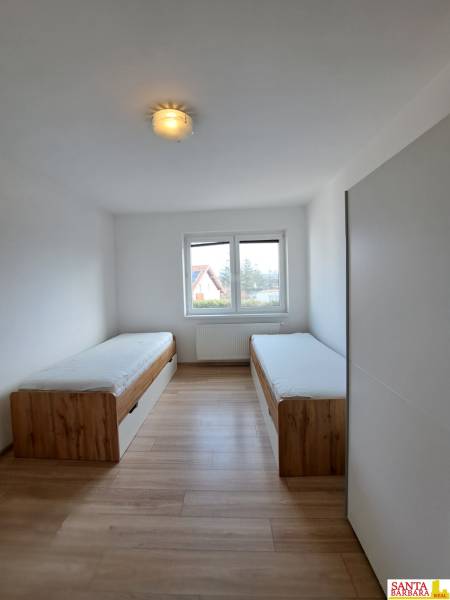 A room in a 4-room apartment with two beds and a floor with a wooden decor.