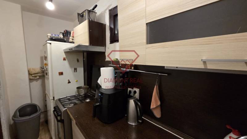 A kitchen in a family house with a wooden decor, containing appliances, cabinets, and a trash can.