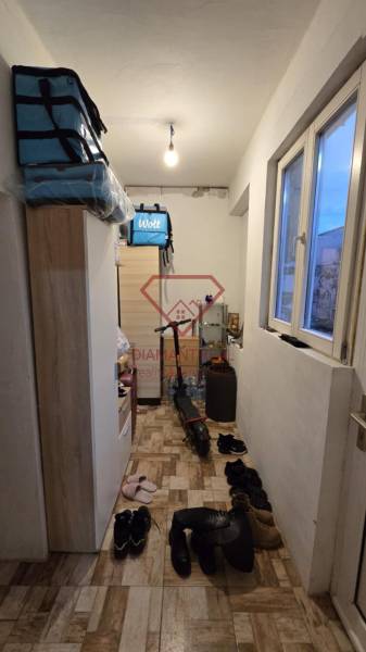 A narrow hallway in a family house with shelves, a window, an electric scooter, and shoes.