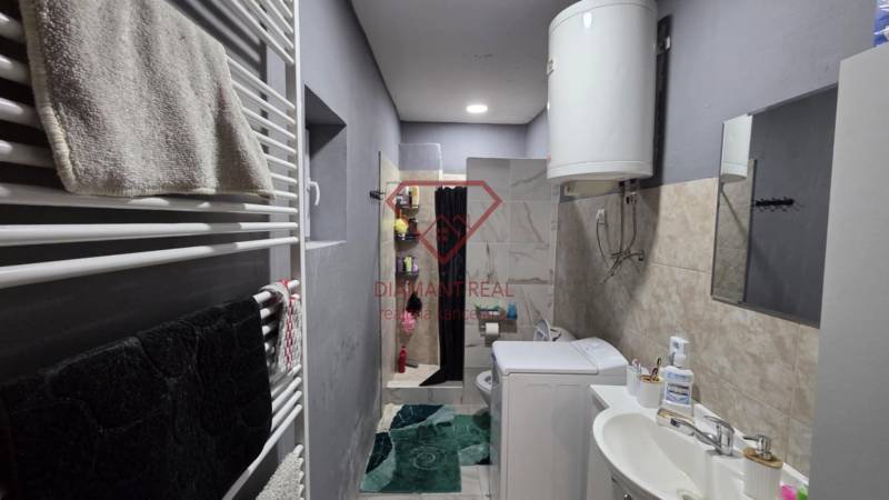 A bathroom in a family house with a sink, washing machine, boiler, and shower.