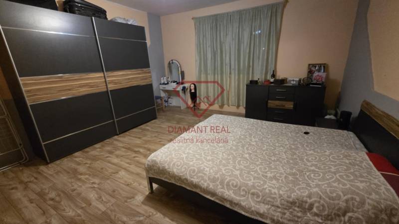Bedroom in a family house with wood-decor flooring, a wardrobe, and a bed.