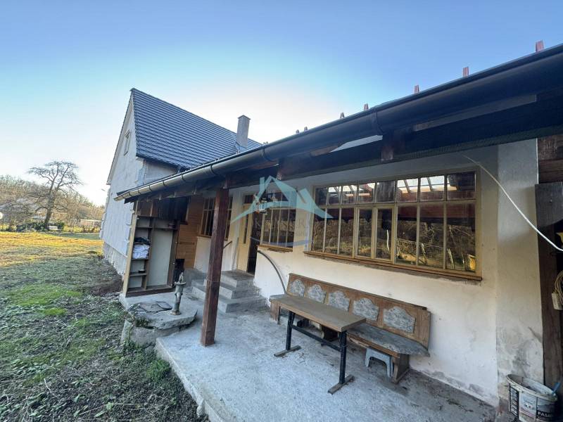 A family house in Demandice with a garden, wooden bench, and outdoor seating area.